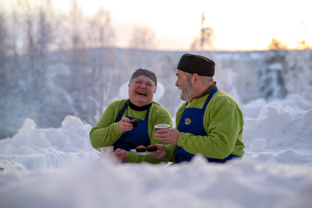 laughing woman and man in snow winter fika coffee